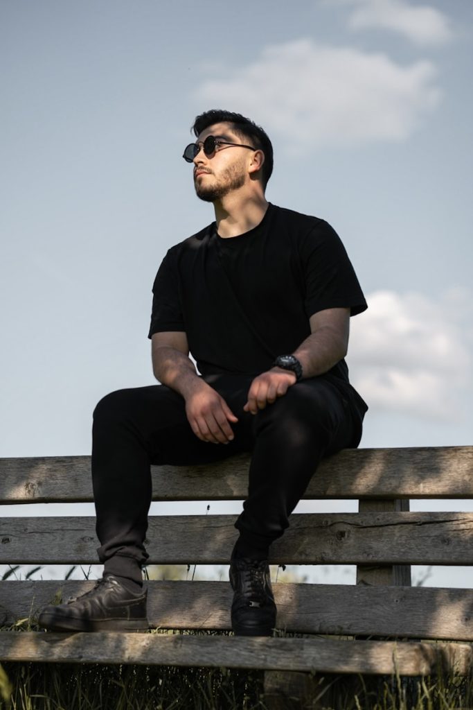 a man sitting on top of a wooden bench